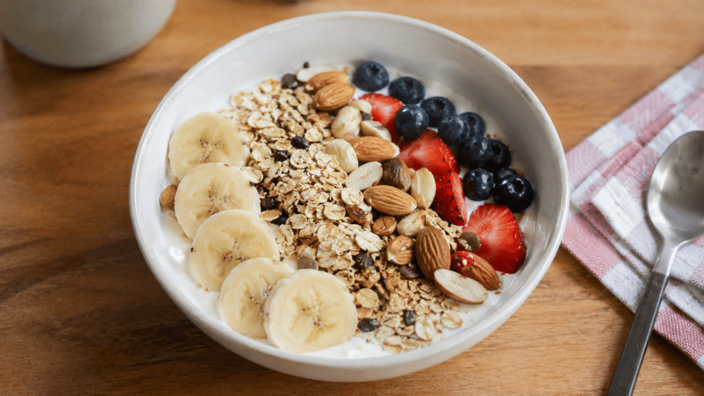 Yoghurt dengan pisang, buah beri, oat, dan kacang-kacangan.